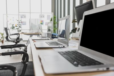Photo selective focus on laptops sitting on conference table in meeting room office with multiple glass windows in background