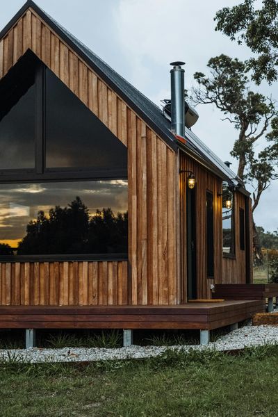 Stylish wooden cabin surrounded by nature during sunset, showcasing modern architecture.
