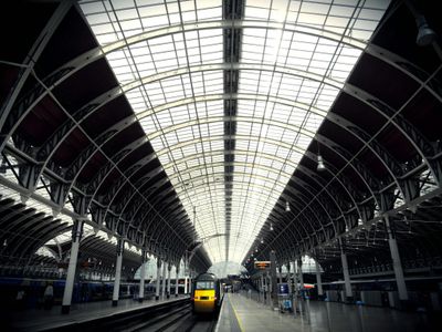 Wide-angle view of a modern train station featuring an arched glass ceiling and empty platforms.
