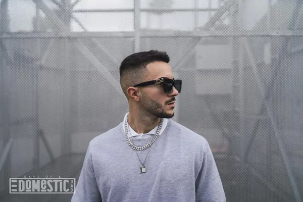 Stylish young attractive man wearing a sweater over a shirt with necklaces and sunglasses