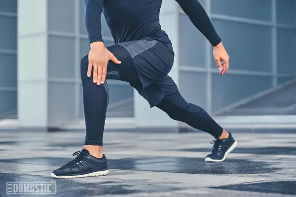 Free photo sporty athletic male is warming up and stretching outdoors over modern building background.