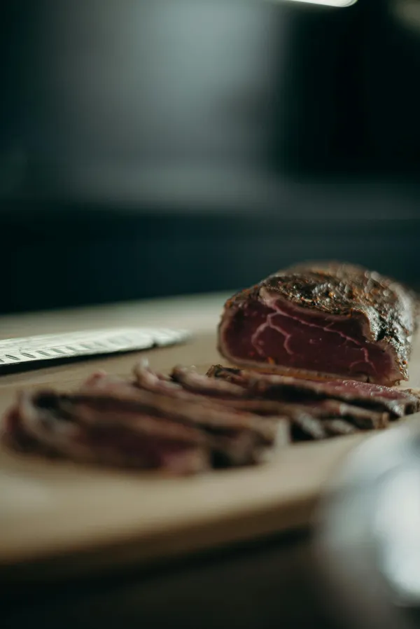 A close-up view of sliced red meat on a wooden cutting board, ideal for culinary and food-related needs.