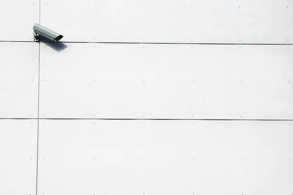 A minimalist image showcasing a single surveillance camera mounted on a stark white wall.