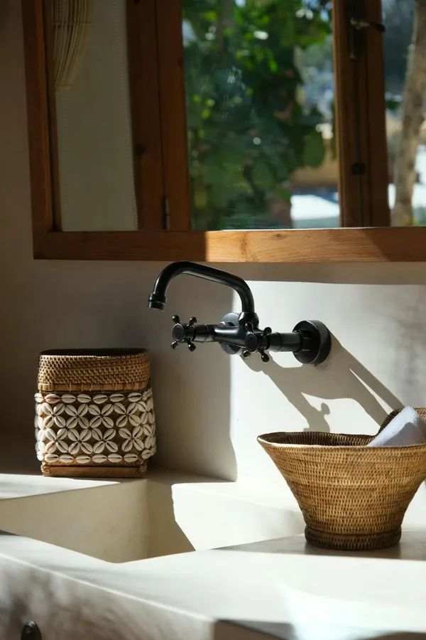 A sunlit bathroom with Mediterranean decor featuring woven baskets and elegant fixtures.