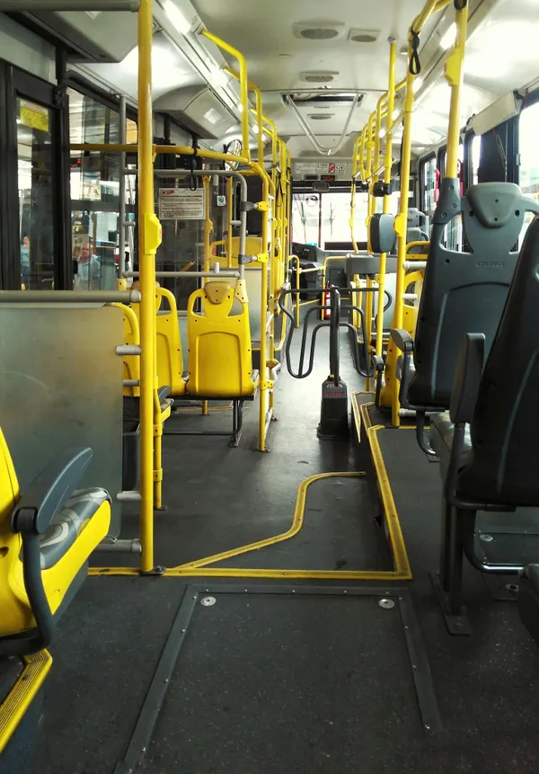 An empty bus with yellow seats and handrails in São Paulo, highlighting urban transportation.