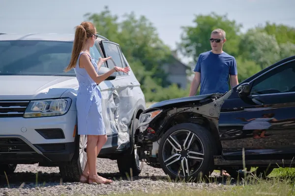 Angry woman and man drivers of heavily damaged vehicles arguing who is guilty in car crash accident on street side. road safe