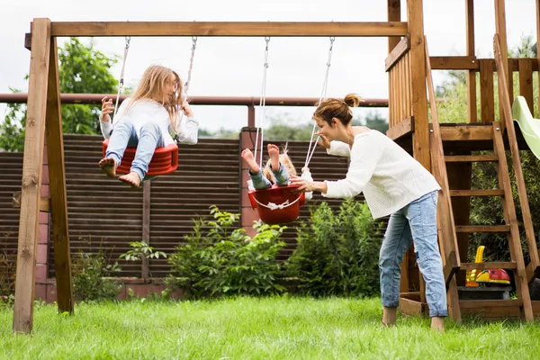Children on the swing. girls sisters swinging on a swing in the yard. summer fun.