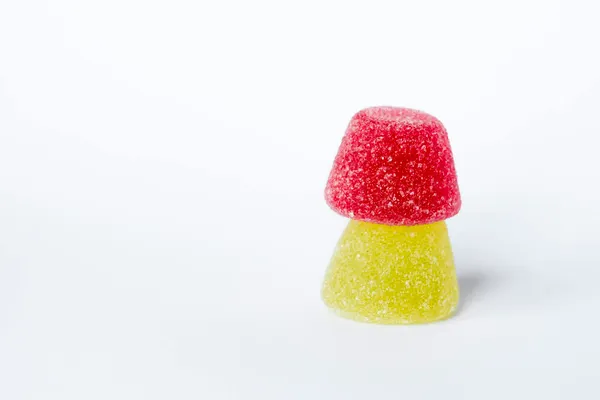 Close-up of red and yellow sugar-coated gummies on a white background.