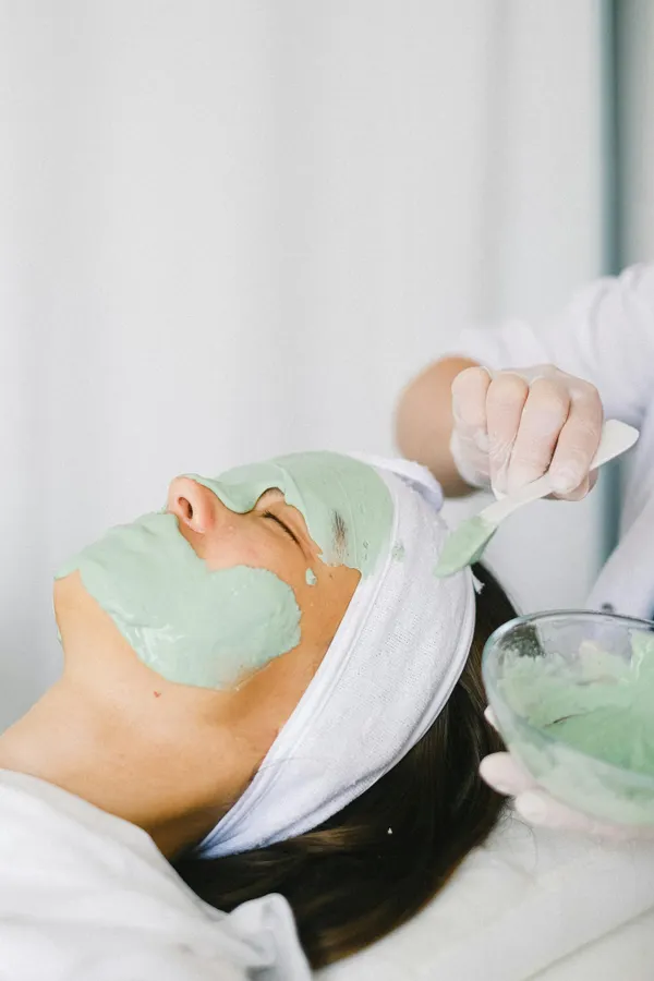 Cosmetician applying facial mask on client face