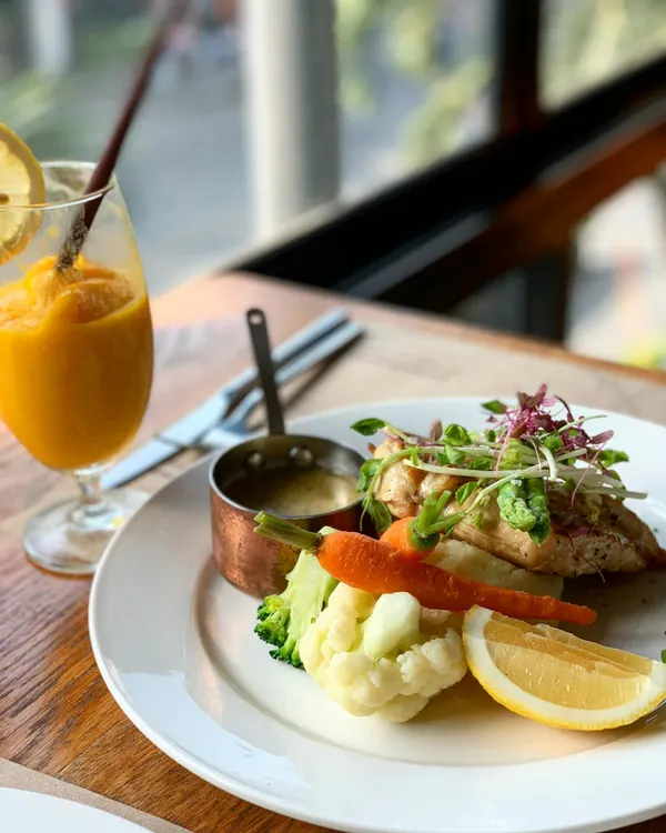 Delicious grilled chicken served with fresh vegetables and a refreshing drink in Bangkok, Thailand.