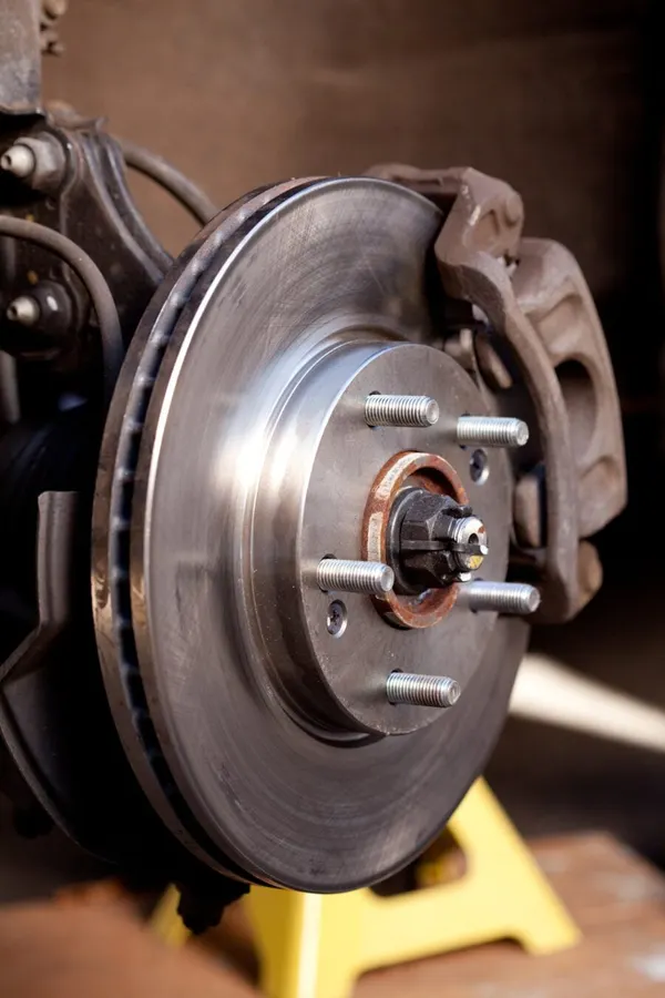 Close up shot of a newly replaced brake rotor and pads for a modern car