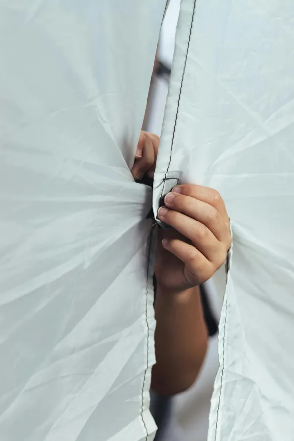 Detailed scene of a hand fastening white fabric with Velcro hooks in a close-up view.