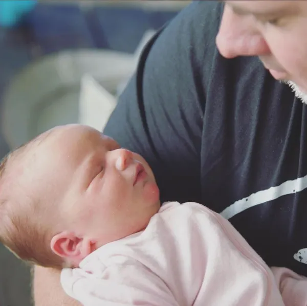 First-time dad lovingly holding his newborn baby in his arms.