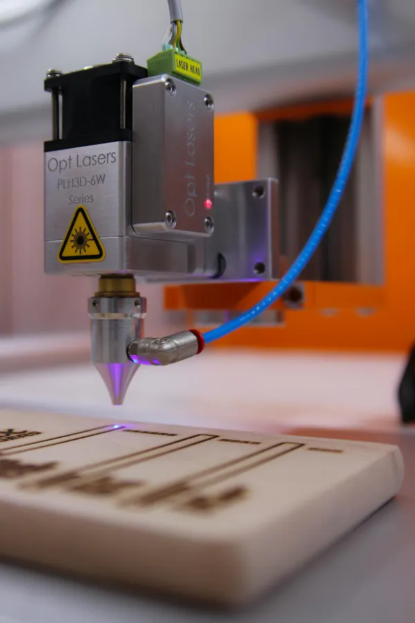 High-tech laser engraving machine working on wooden surface.