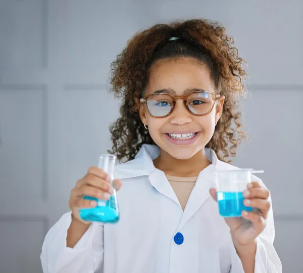 Photo how would you react. cropped portrait of an adorable little girl wearing a labcoat while holding two containers of blue