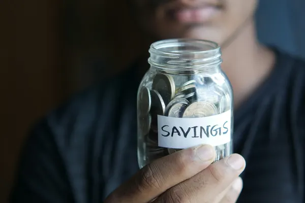 man holding a jar of coins with a white lable savings