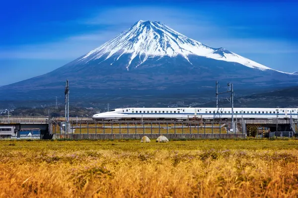 Shinkansen bullet train passing in front of snow-capped Mount Fuji in Japan