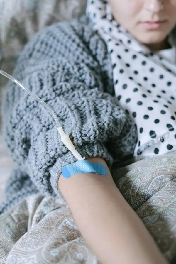 Portrait of a woman receiving chemotherapy treatment in a cozy home setting.