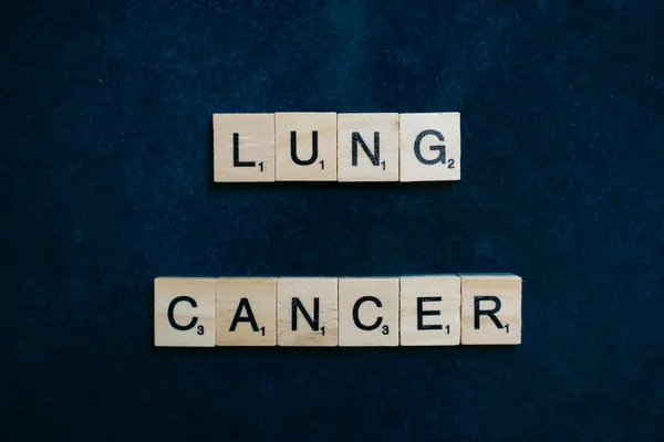 Scrabble tiles spelling lung cancer on dark background symbolizing awareness.