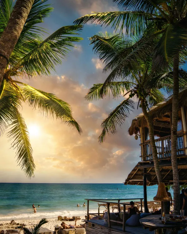 Stunning sunset view at Tulum Beach, Mexico, showcasing coconut palms and tranquil ocean.