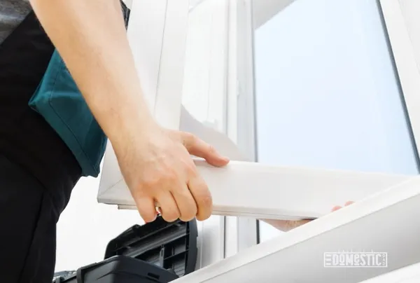Professional handyman installing window at home.