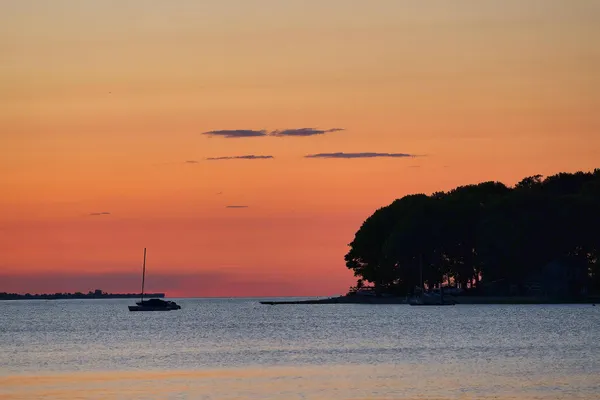 Tranquil sunset view with a sailboat silhouette on Norwalk Harbor, Connecticut.