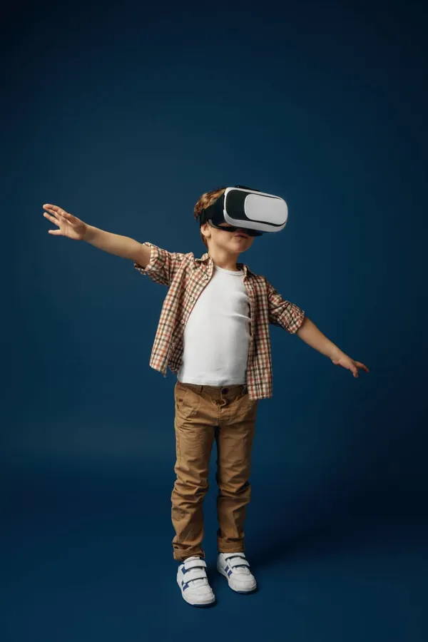 Weightless in the sky. little boy or child in jeans and shirt with virtual reality headset glasses isolated on blue studio ba