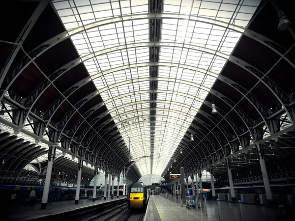 Wide-angle view of a modern train station featuring an arched glass ceiling and empty platforms.