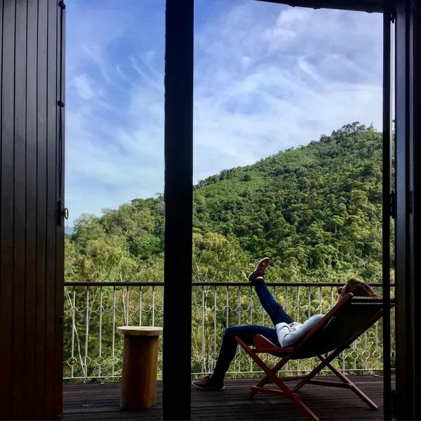 Woman enjoying a serene moment on a balcony overlooking lush Brazilian mountains.