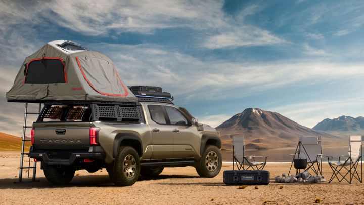 2025 Toyota Tacoma Trailhunter with rooftop tent and overlanding gear at a desert campsite, mountains in the background.