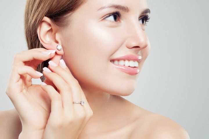 Beautiful bride in puts on diamond earring. Beauty model girl in wedding jewelry, perfect face closeup