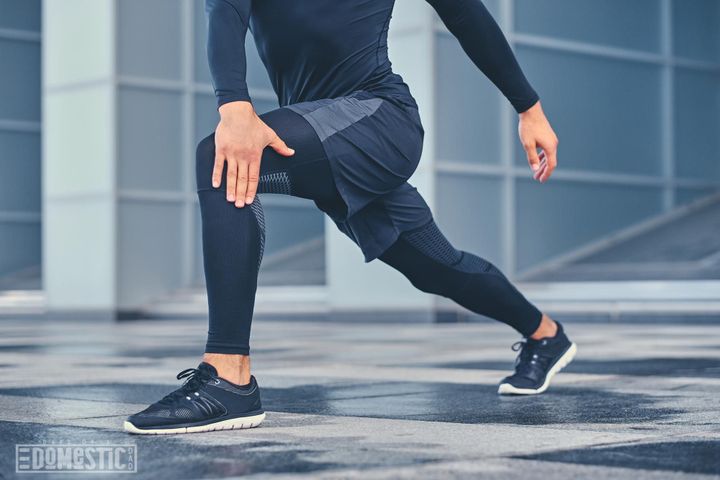 Free photo sporty athletic male is warming up and stretching outdoors over modern building background.