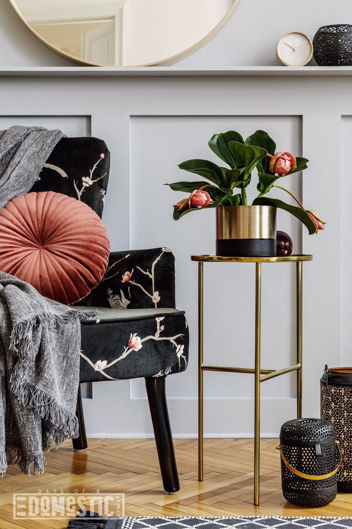 Modern concept of home staging with design armchair, round mirror, gold coffee table, pillow, plaid, lanterns, shlef, grey wa