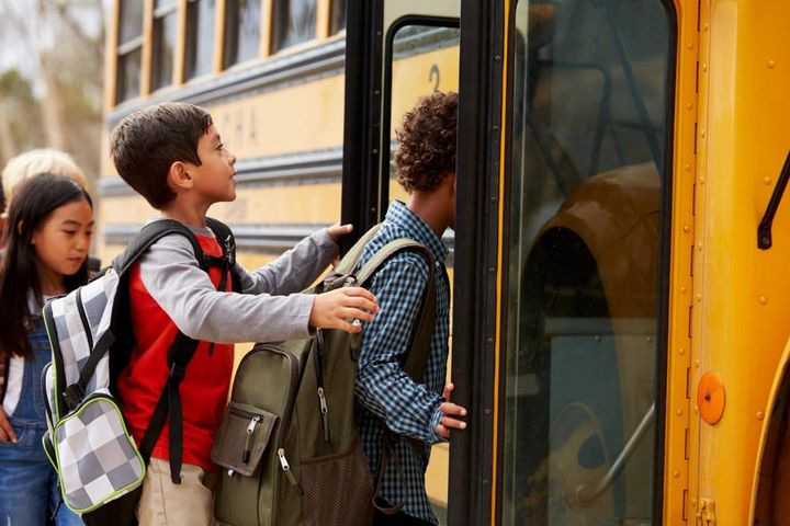 Elementary school children boarding a yellow school bus in the morning