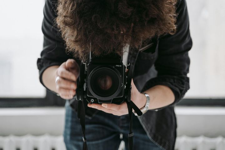 A young photographer captures the moment with a vintage film camera indoors.