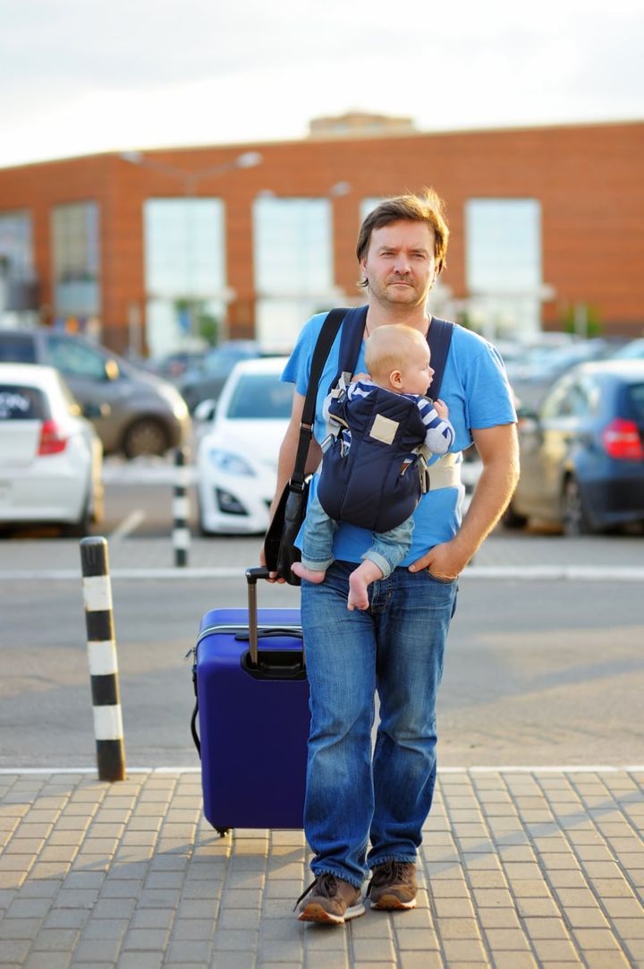 man carrying infant on chest airport