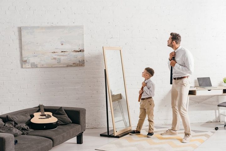 full length view of son and father in formal wear standing near mirror