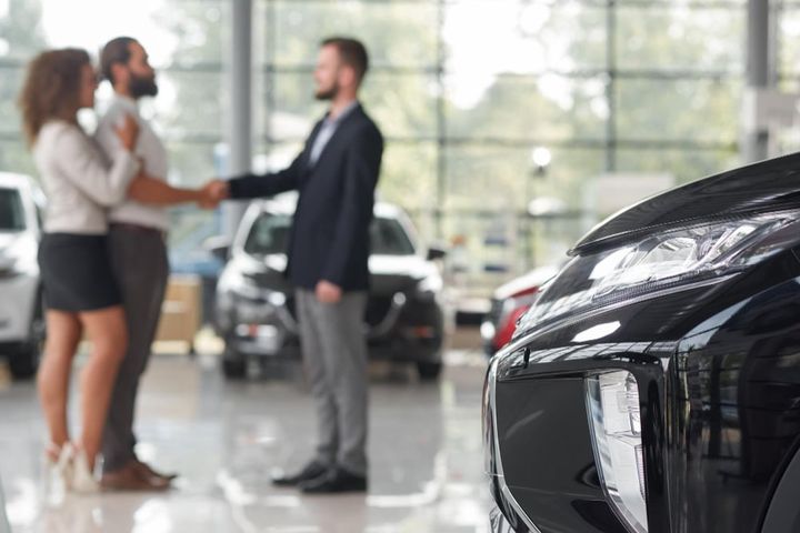 Free photo car headlight couple making deal with car dealer behind