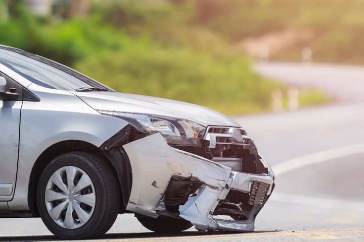 Front of silver car get damaged by crash accident on the road.