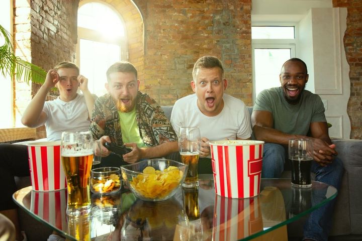 Group of excited friends playing video games at home. male gamers or fans spending time and having fun together at home