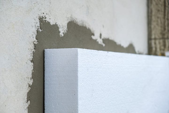 Photo installation of styrofoam insulation sheets on house facade wall for thermal protection.