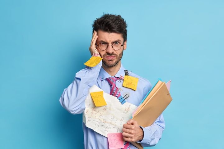 Intensed serious unshaven male student has headache because of long work busy preparing for math exam or makes project has de