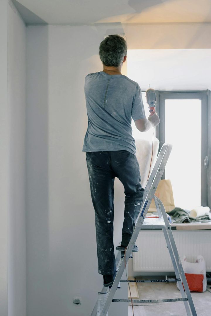 Male builder with instrument in apartment