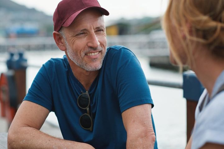 Man woman and harbor with happy conversation on travel vacation or date by ocean in summer sunshine senior couple talk and li