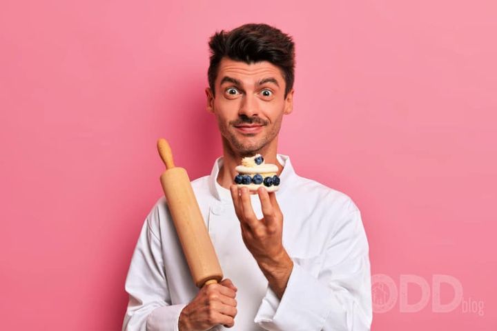 Pastry chef holds cream tasty cake, tells recipe of delicious confectionery, works in cafe as cook, dressed in white uniform