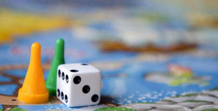 A playing cube and two chips on a board game