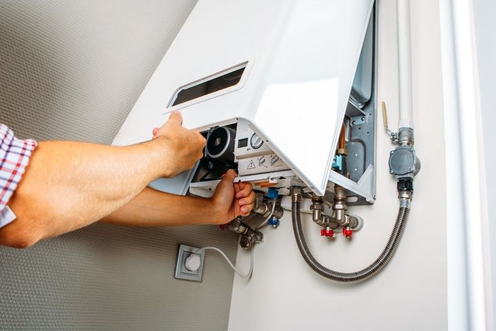 Plumber attaches trying to fix the problem with the residential heating equipment. repair of a gas boiler