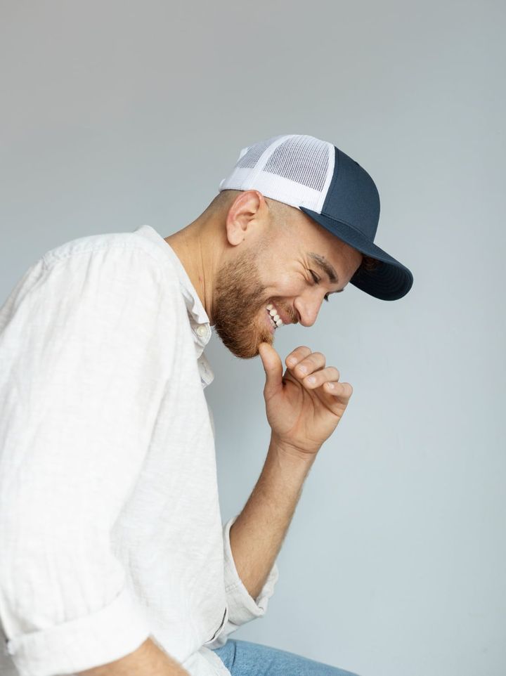 Smiley man posing with trucker hat side view