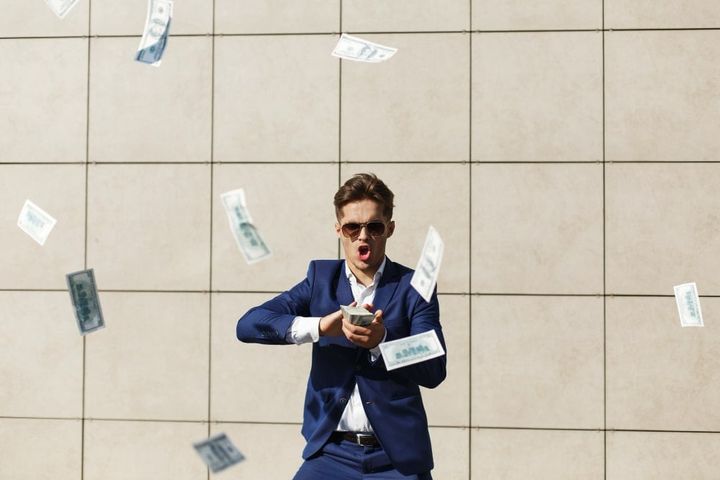 Young businessman throughs around money and dances on the street