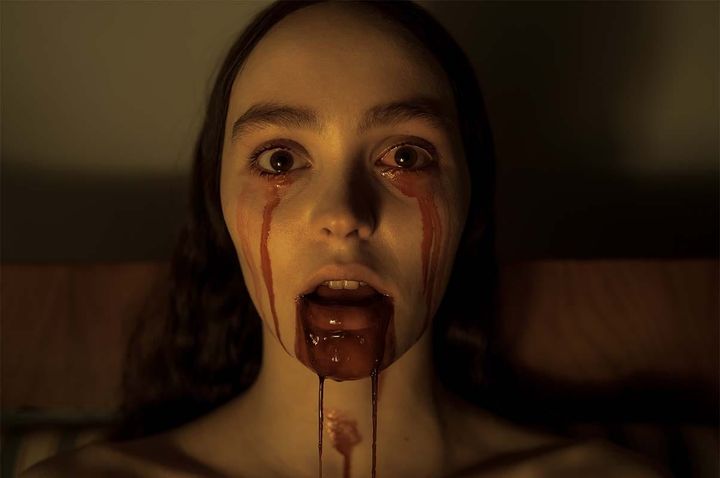Official movie poster for Robert Eggers' Nosferatu (2024) featuring Lily-Rose Depp as Ellen Hutter being loomed over by the dark shadow of Bill Skarsgård’s Count Orlok.